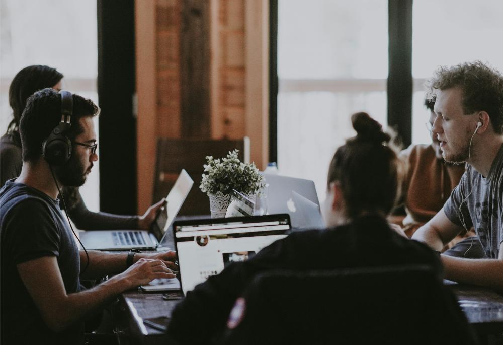 Group of professionals meeting together while working on their laptops